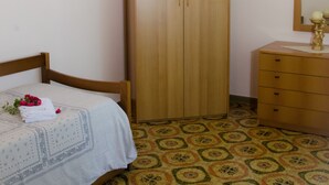 Une chambre à coucher avec un lit, une armoire en bois, une commode et un sol à motifs.
