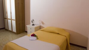 Une chambre d’hôtel avec un lit, une table de chevet, une lampe et une armoire.