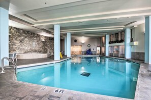Una piscina interior con pared de piedra, una silla de salvavidas y un indicador de profundidad de 6 pies.