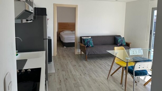 A modern, compact living space with a kitchenette, a sofa, a glass dining table, and a bed. - 4Grados Sur Guatemala City zona 4 Rooftop view (Ciudad de Guatemala)