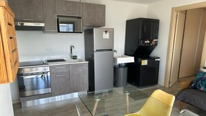 A modern kitchen with grey cabinets, stainless steel appliances, and a glass dining table with two chairs. - 4Grados Sur Guatemala City zona 4 Rooftop view (Ciudad de Guatemala)