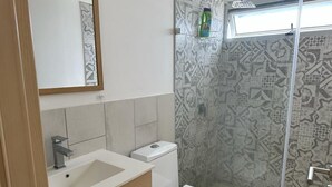A bathroom with a white sink, a toilet, and a shower area with patterned tiles. - 4Grados Sur Guatemala City zona 4 Rooftop view (Ciudad de Guatemala)