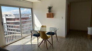 A balcony with a glass table and chairs, a potted plant on the wall, and a view of a cityscape. - 4Grados Sur Guatemala City zona 4 Rooftop view (Ciudad de Guatemala)