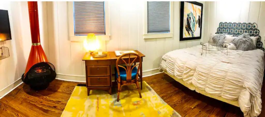 Ein Schlafzimmer mit Bett, Schreibtisch, Stuhl, Lampe und Heizkörper.