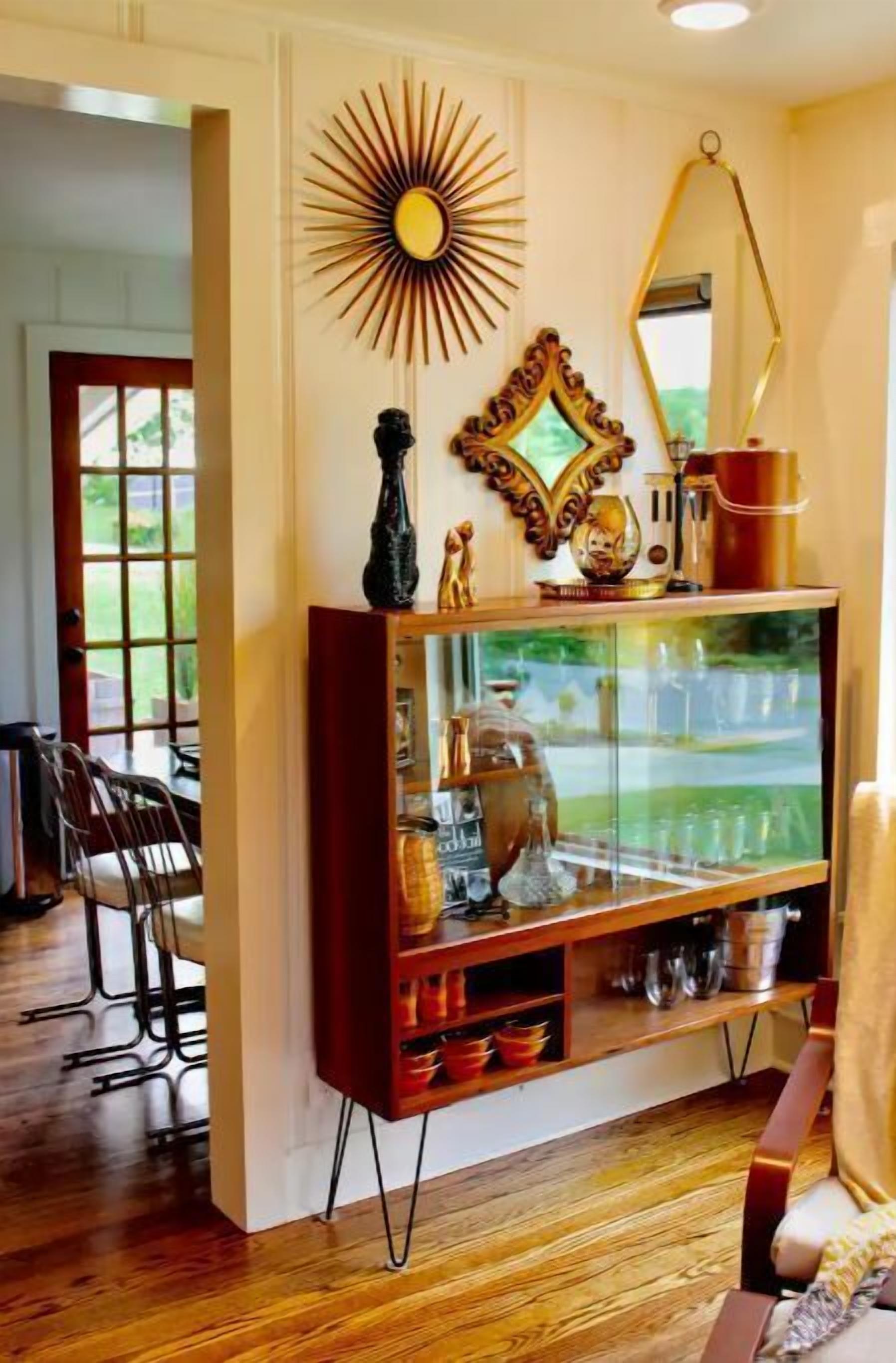Ein modernes Wohnzimmer mit Holzboden, einem Glastisch mit Dekorationsobjekten und einer Wanddekoration im Sonnenstrahl-Design.