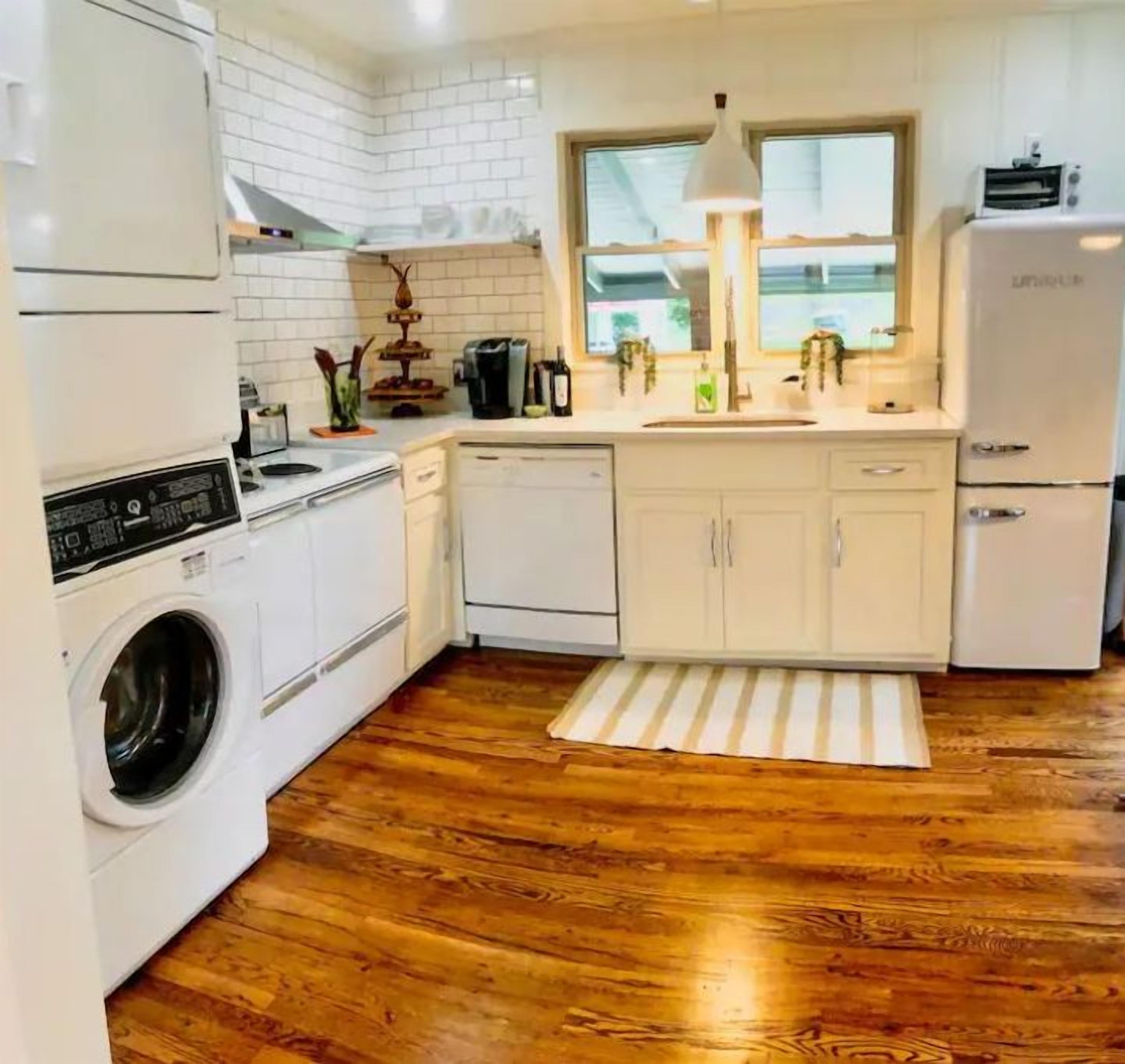 Une cuisine compacte avec des meubles blancs, un lave-linge, un lave-vaisselle et un réfrigérateur.