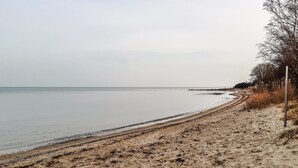 Ein sandiger Strand mit freiem Blick auf das Wasser und einem Weg entlang der Küste.