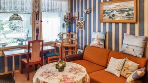Ein gemütliches Wohnzimmer mit einer gestreiften Wand, einem Holztisch mit Stühlen, einer Couch und einem Gemälde.
