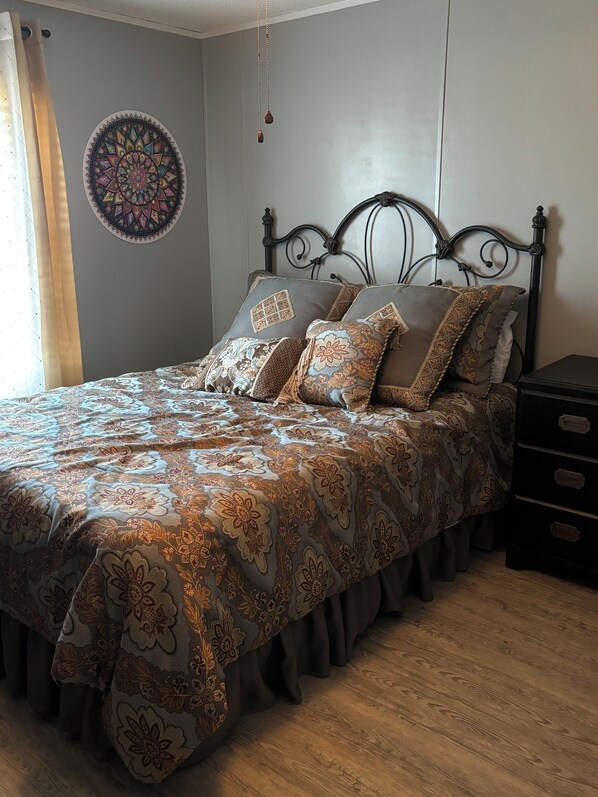A bedroom with a bed, a headboard, a wall hanging, a nightstand, and a dresser. - The Ranch House (Story)