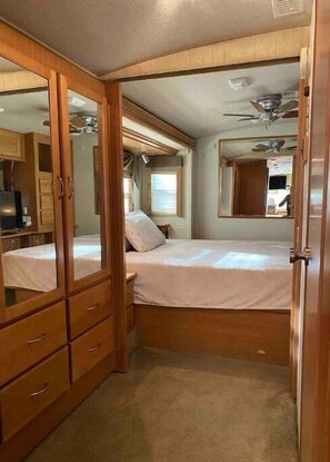Un dormitorio pequeño con cama, armario, espejo y ventilador de techo.