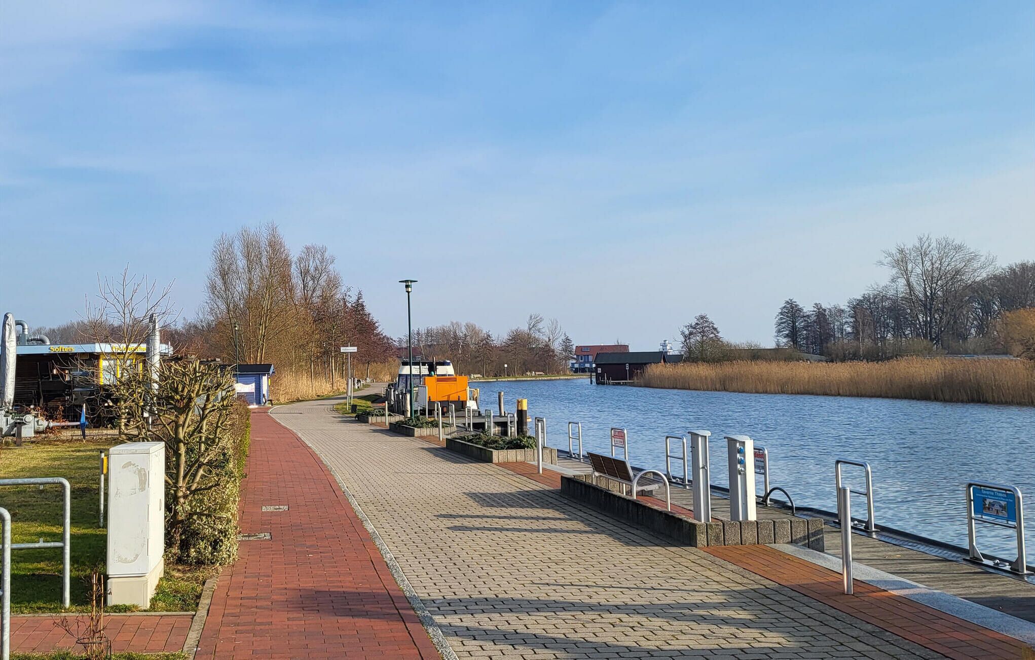 A riverside walkway with a dock, a small boat, and a building labeled "Soeters."