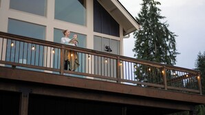 A balcony with a railing, a person holding a child, and a large window. - Modern Chalet with Lake Views in Marina Area (Mossyrock)
