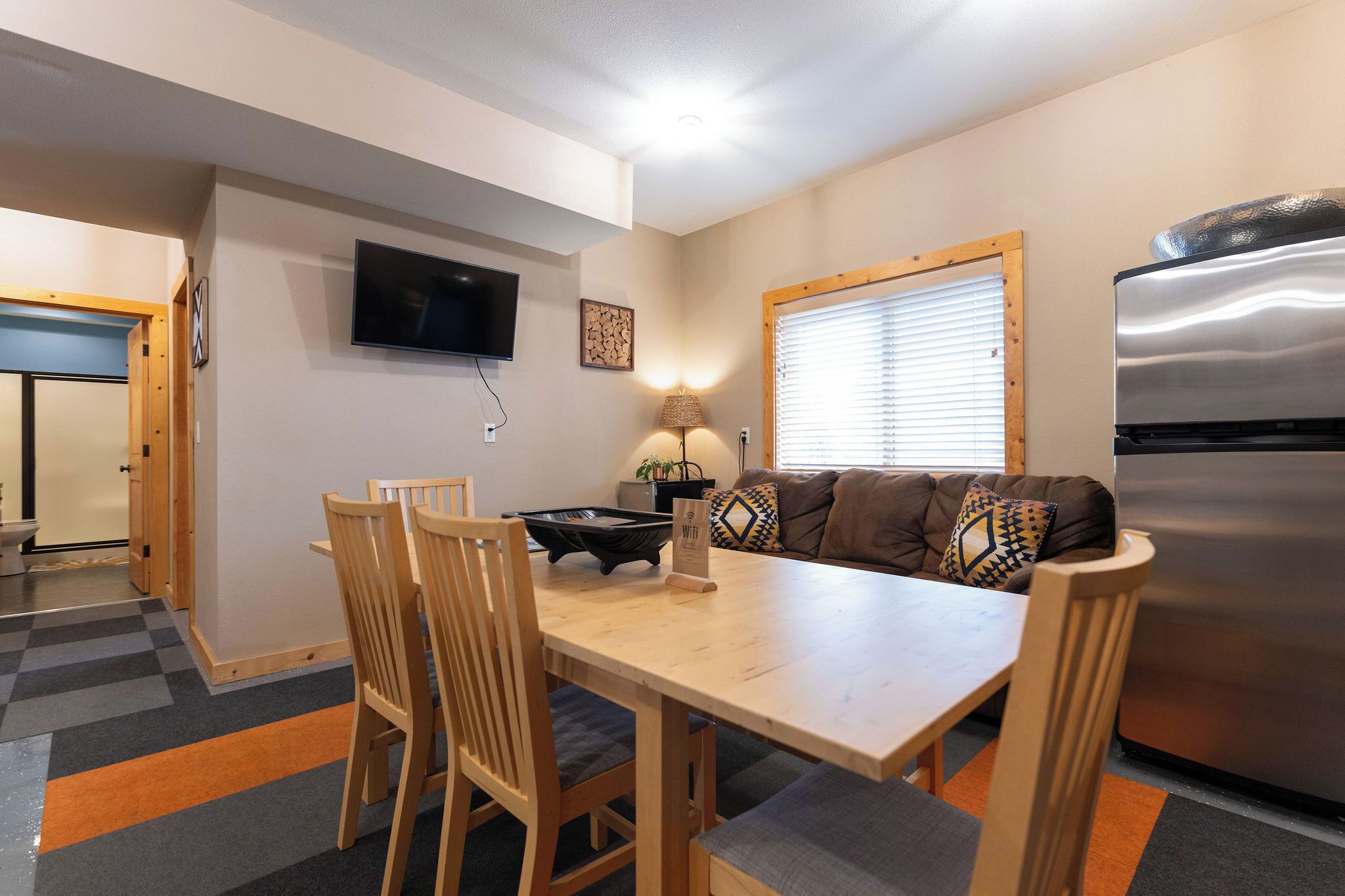 A compact living space with a dining area, a sofa, a TV, and a refrigerator.