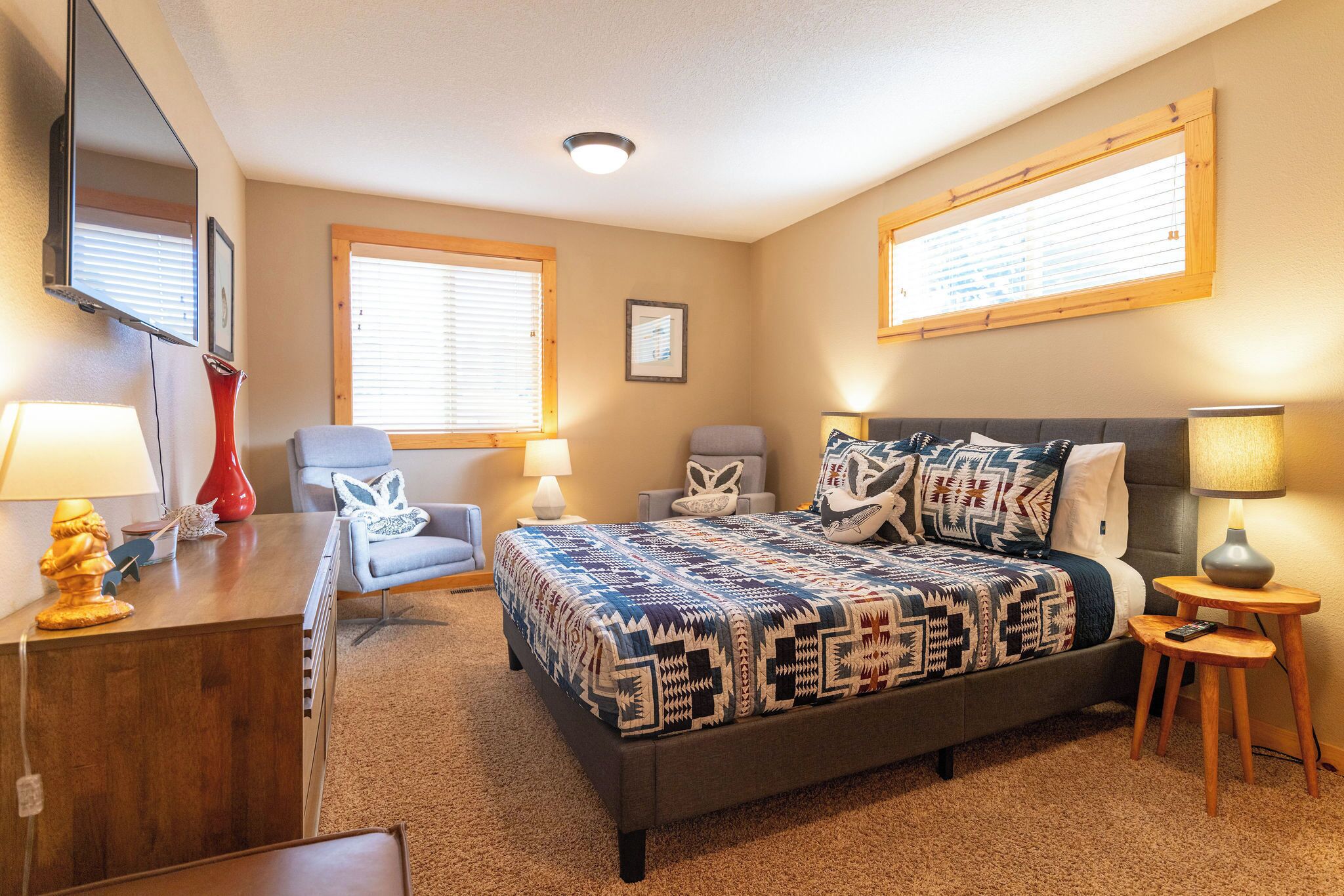 A bedroom with a bed, two chairs, a desk, and a lamp.