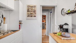 Ett modernt kök med vita skåp, en bänkskiva i trä, en kaffebryggare och en klocka på väggen.