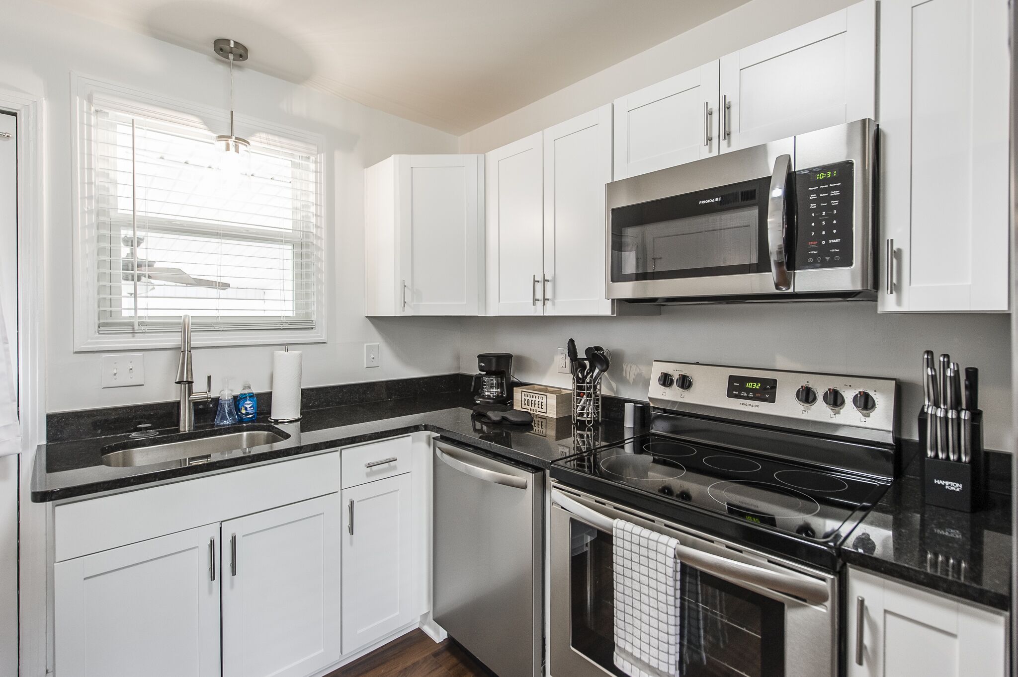 A modern kitchen with white cabinets, a stainless steel microwave, a stove, and a dishwasher.