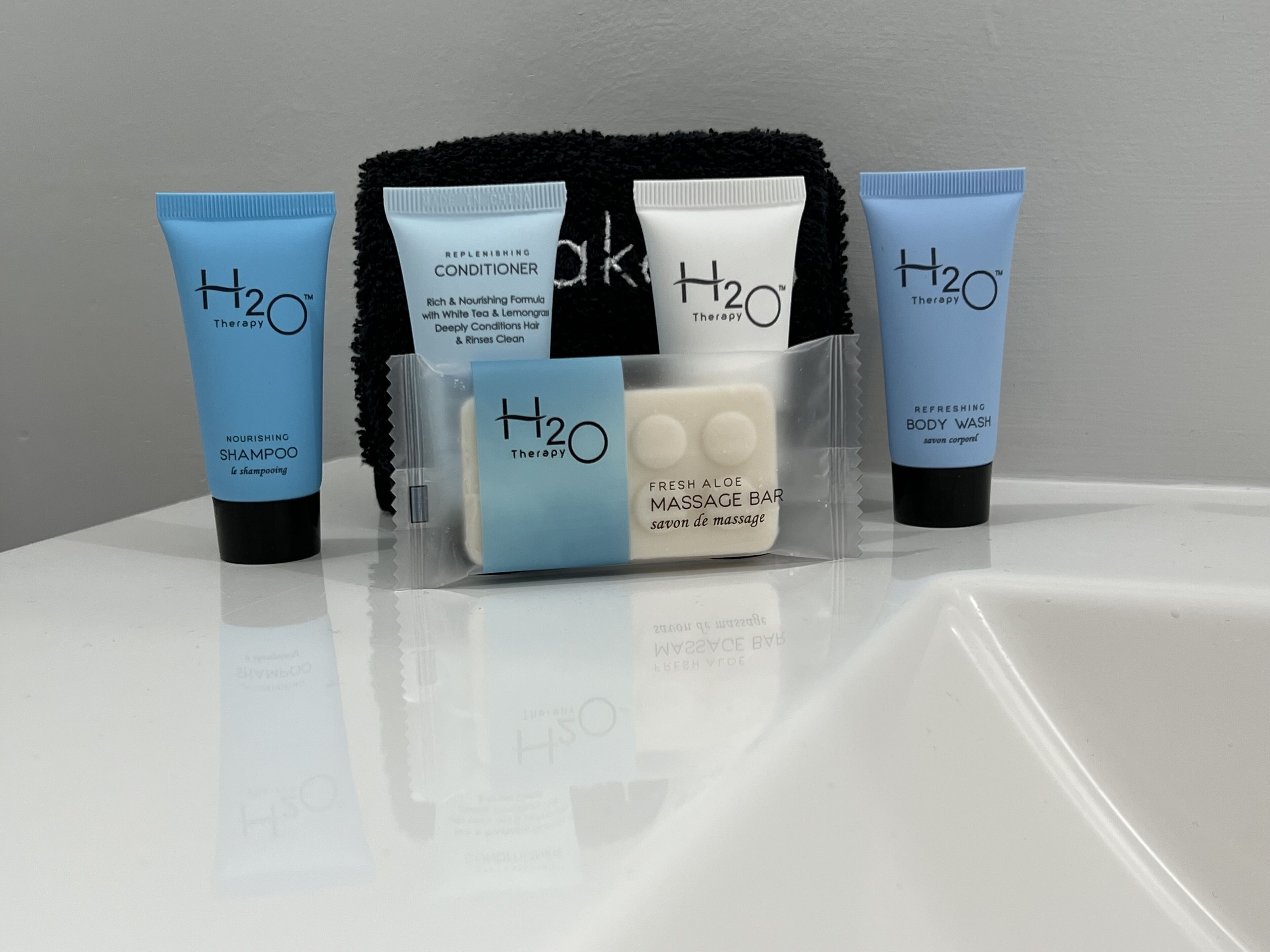A set of H2O Therapy skincare products including a nourishing shampoo, conditioner, body wash, and a fresh aloe massage bar.