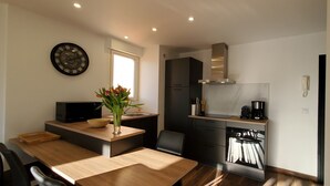 A modern kitchen with a wooden dining table, a vase with flowers, a microwave, and a built-in oven. - Fréjus-Plage, Sea view, T2, 38m2, 4 people, refurbished, air conditioning, magnificent (Fréjus)