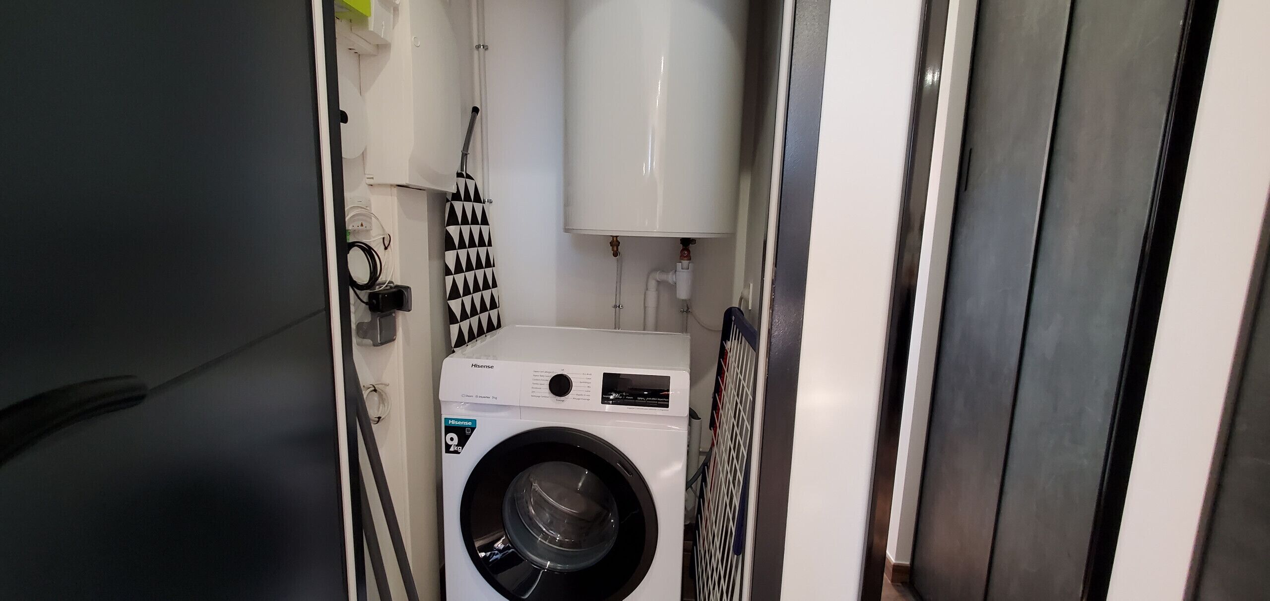 A compact laundry room with a front-loading washing machine and a drying rack.