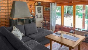 A cozy living room with a brick wall, a fireplace, a sofa, and a dining table. - Amazing home in Arboga with sauna (Arboga)
