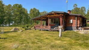 A log cabin with a porch, outdoor seating, and a view of the surrounding forest. - Amazing home in Arboga with sauna (Arboga)