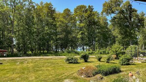 A well-maintained grassy area with a variety of trees and shrubs, a small building, and a fenced area. - Amazing home in Arboga with sauna (Arboga)