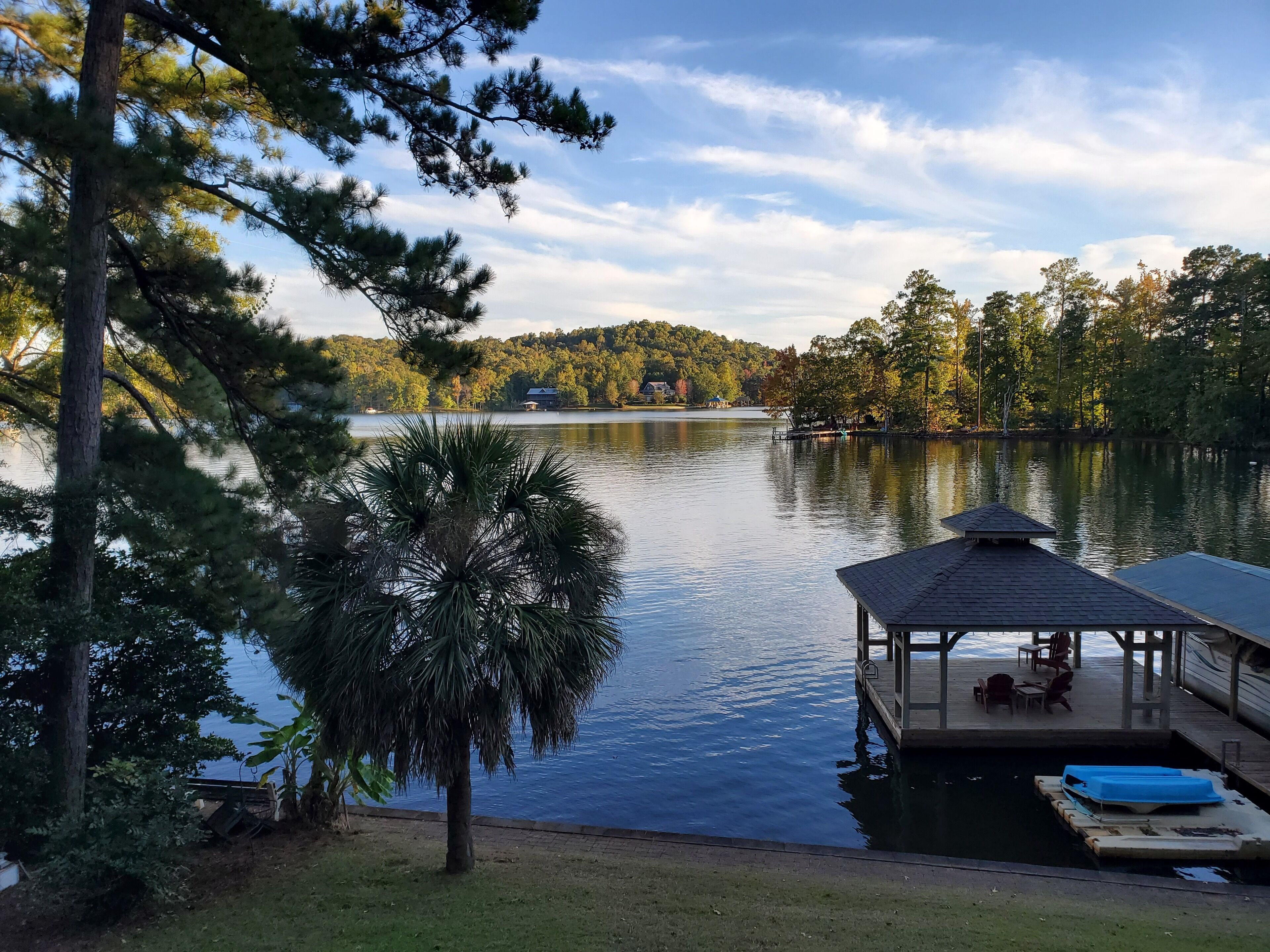 A lakeside dock with a covered seating area and a small boat.