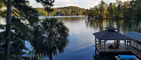 A lakeside dock with a covered seating area and a small boat.