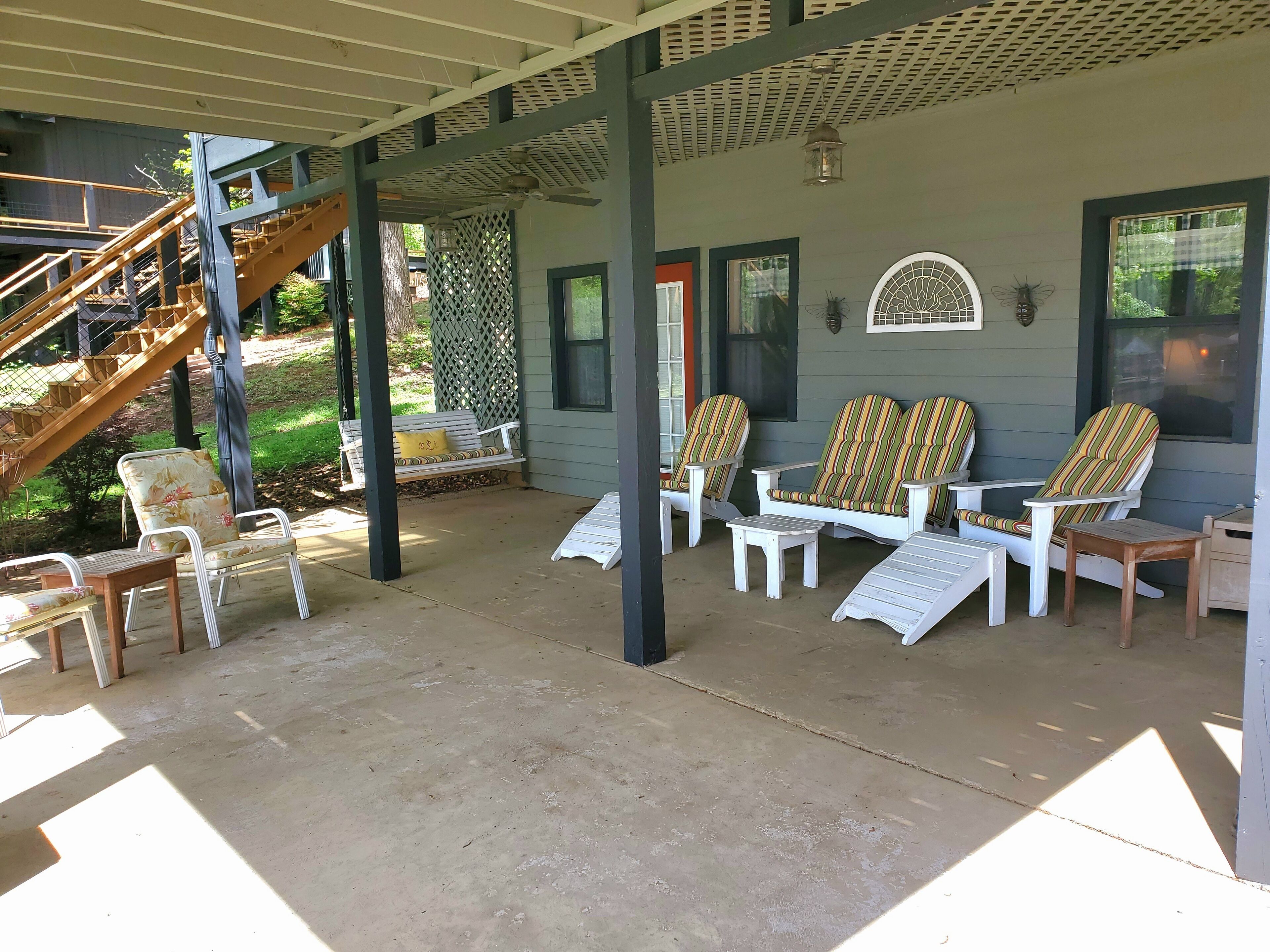 A covered porch with outdoor seating, a staircase, and a view of the surrounding area.