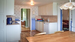 Una cocina compacta con armarios blancos, una mesa de comedor de madera y una cafetera azul.