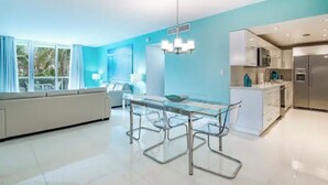 A modern kitchen with a dining area, large windows, and a view of greenery outside. - Beautiful Vacation Rental Directly on beach (Hollywood)