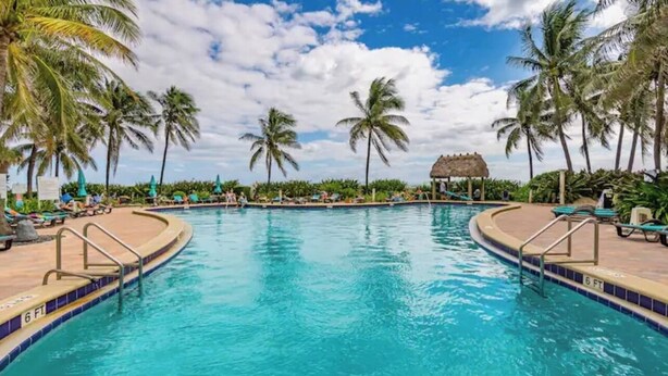 A pool with a 6 ft depth marker, surrounded by palm trees and lounge chairs. - Beautiful Vacation Rental Directly on beach (Hollywood)