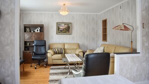 Una sala de estar con sofá, sillones, una mesa de centro y una estantería.