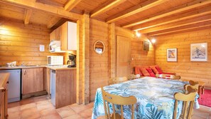 A wooden cabin interior with a kitchen, dining area, and a cozy seating space. - Cosy chalet 4/6 ppl with balcony (Morillon)