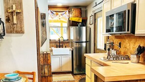 Une cuisine compacte avec des meubles en bois, un réfrigérateur en acier inoxydable, un four à micro-ondes et un évier.