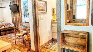 Une pièce confortable avec un plancher en bois, un lit, une télévision, un tableau et un miroir.