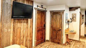 Un couloir aux murs recouverts de bois, avec un téléviseur fixé au mur et une porte en bois.