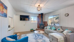 Una sala de estar acogedora con chimenea, un sofá azul y una mesa redonda de centro.
