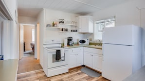 Una cocina moderna con armarios blancos, horno empotrado, microondas y refrigerador.