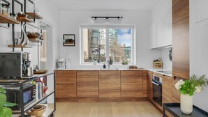 Een moderne keuken met houten kastjes, een inbouwoven en een groot raam met uitzicht op de stad.