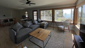 Un salon spacieux avec un canapé d’angle, une table basse et un balcon offrant une vue sur l’océan.