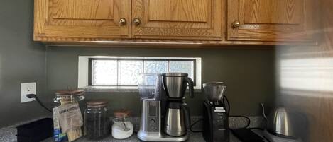 Una cocina con armarios de madera, un ventanal y varios electrodomésticos, incluyendo una cafetera y una licuadora.
