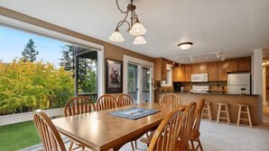 A modern kitchen with wooden cabinets, a central island, and a dining area with a large table and chairs.
