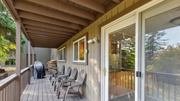 A covered deck with outdoor seating and a sliding glass door leading to a deck area.