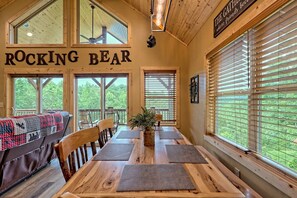 A dining area with a wooden table, chairs, and a view of the outdoors.