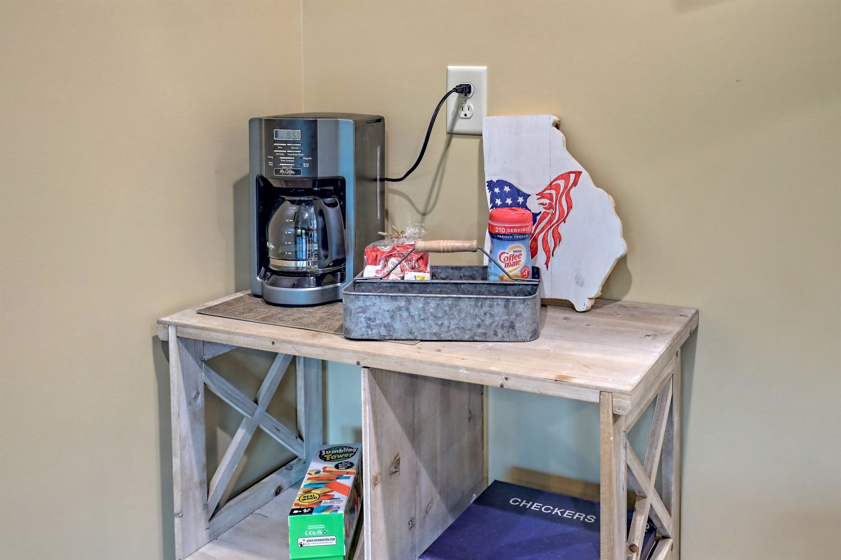 A coffee maker, a box of JUMBLING TOYS, and a coffee bag on a wooden table.