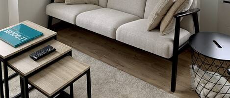 A modern living room with a sofa, a small table, a remote control, and a picture on the wall.