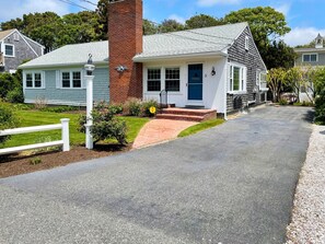 A single-story house with a brick chimney, a blue door, and a small porch.
