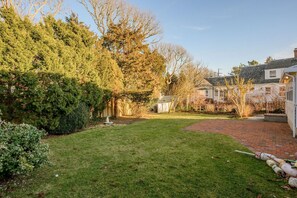A well-maintained backyard with a grassy lawn, a brick pathway, and a small garden area with a fountain.
