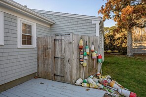 A house with a wooden garage door and a pile of colorful buoys outside.